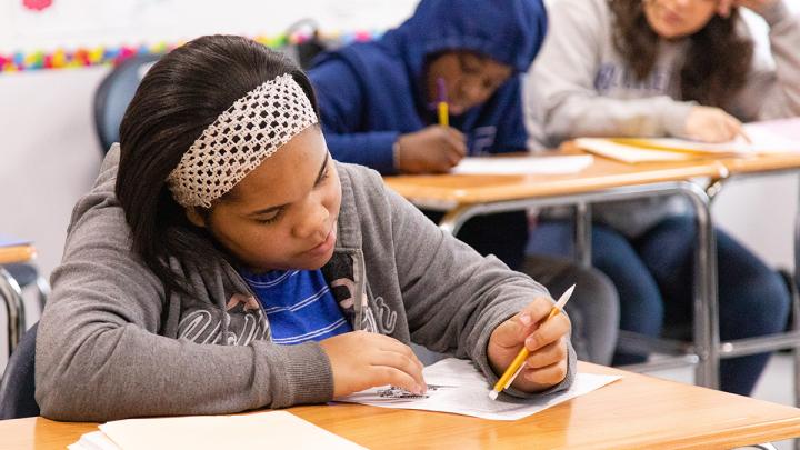 Student sitting at desk writing on paper
