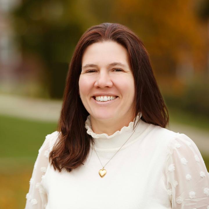 Kelly Pearson standing outside on the University of Rochester's River Campus, smiling at the camera during a sunny day.