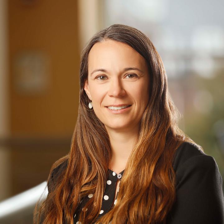 Melissa Staloff standing in the Warner School's LeChase Hall, smiling at the camera.